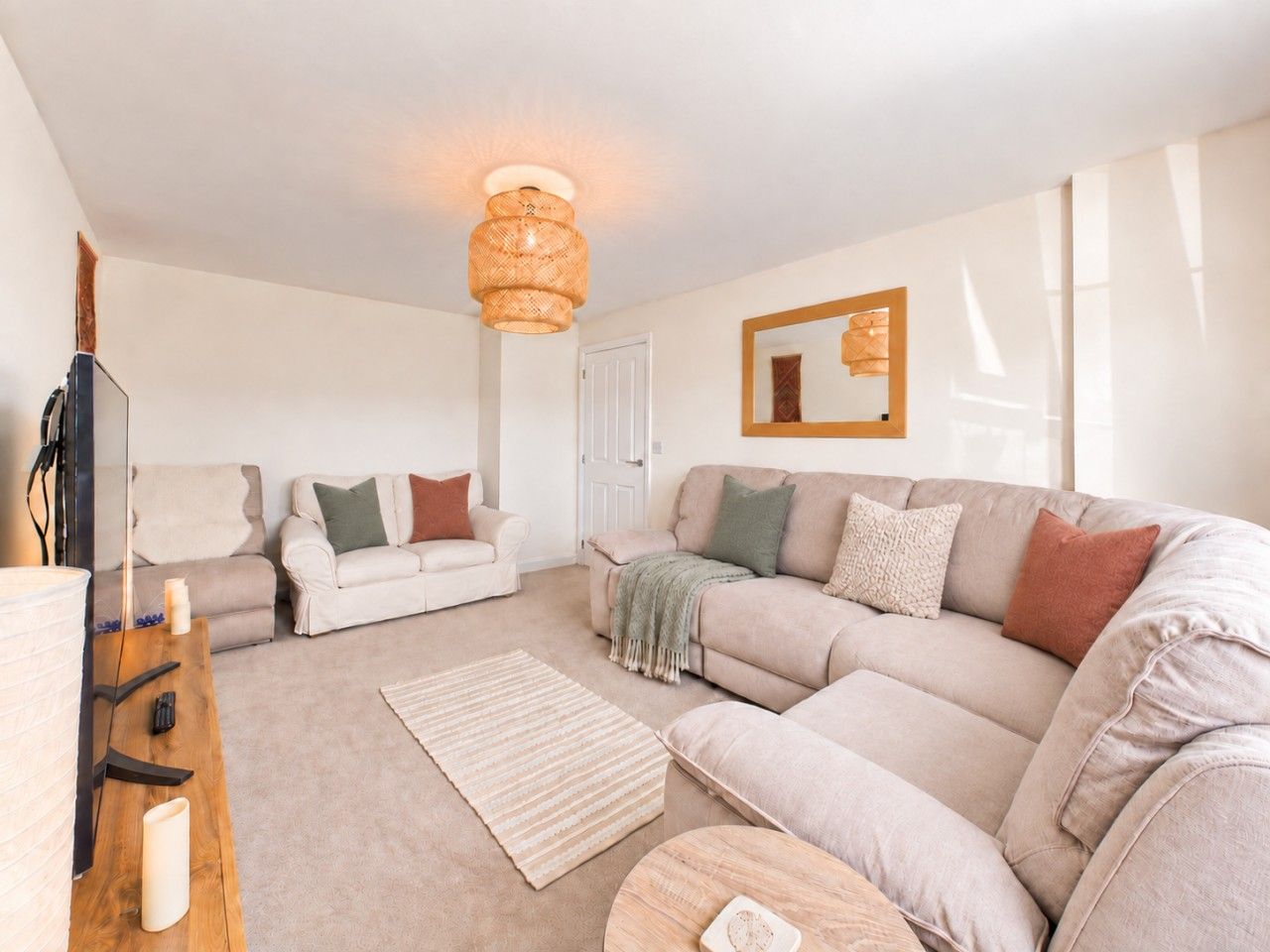 A modern living room with a sectional sofa, a coffee table, a TV, and a large window.