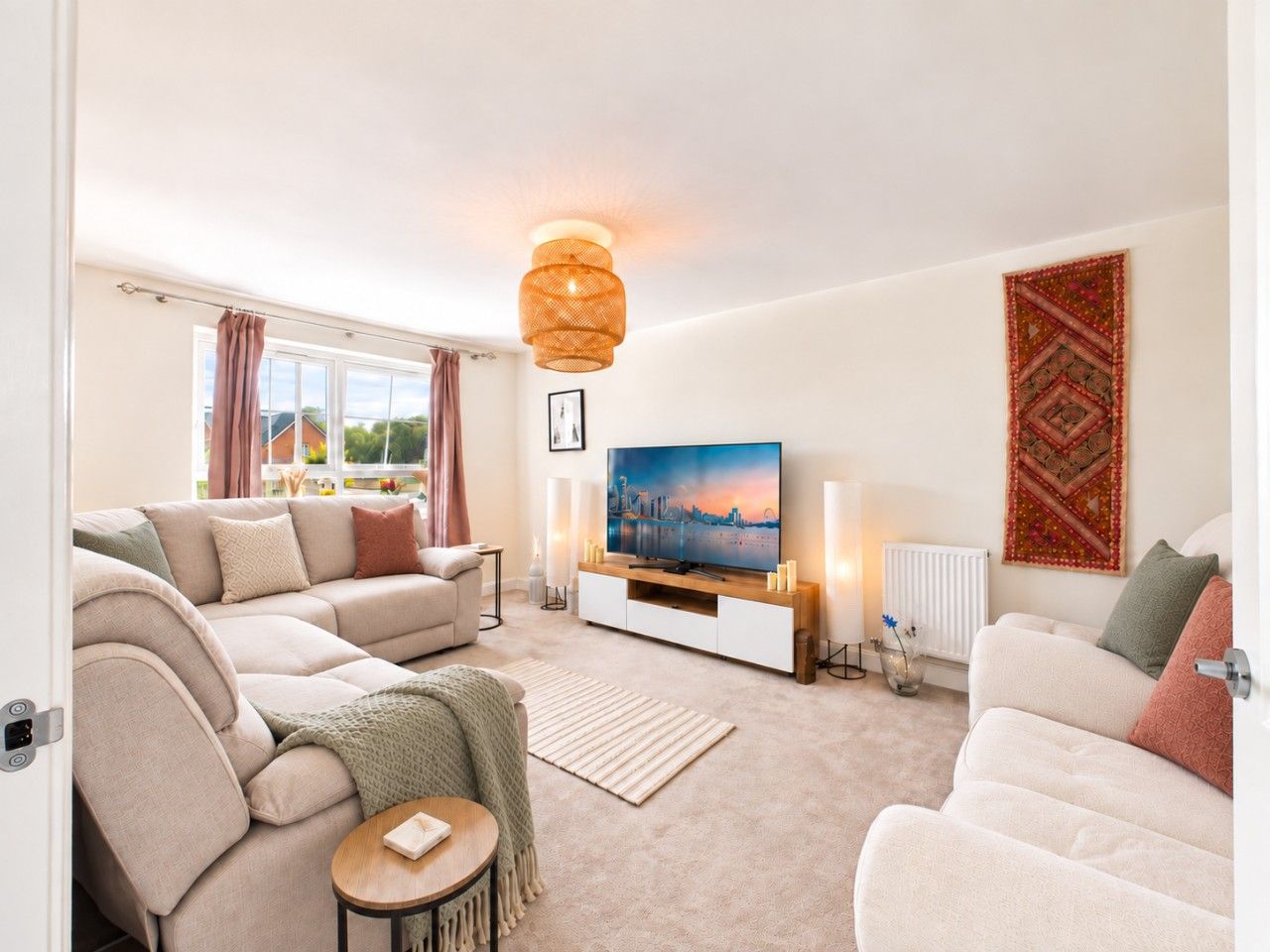 A modern living room with a sofa set, a flat-screen TV, and a decorative wall hanging.