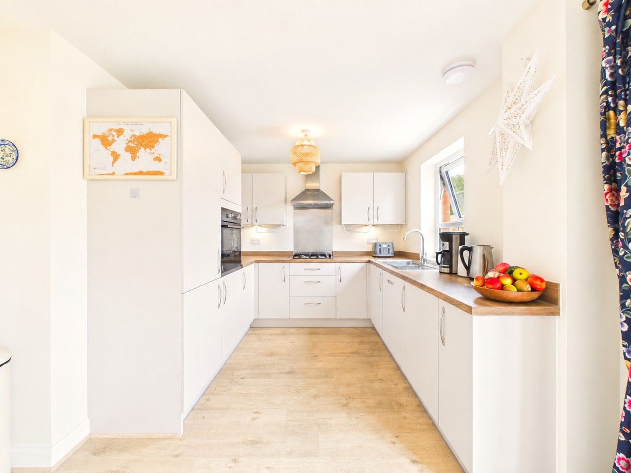 A modern kitchen with white cabinets, a central island, and a fruit bowl on the counter.