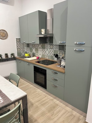 A kitchen with grey cabinets, a wooden countertop, a built-in oven, and a tiled backsplash. - Cozy apartments in Naples, 3 km from Naples Central Station. (Napoli)