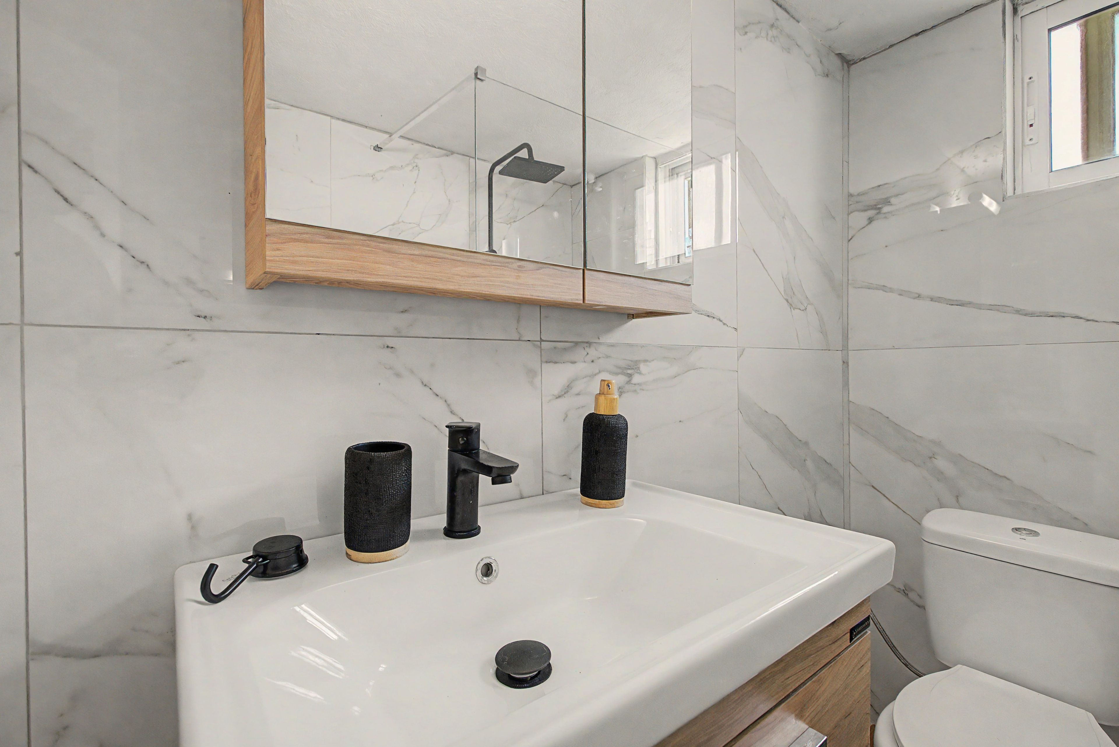 Een badkamer met een wit wastafel, een spiegel en een toilet.