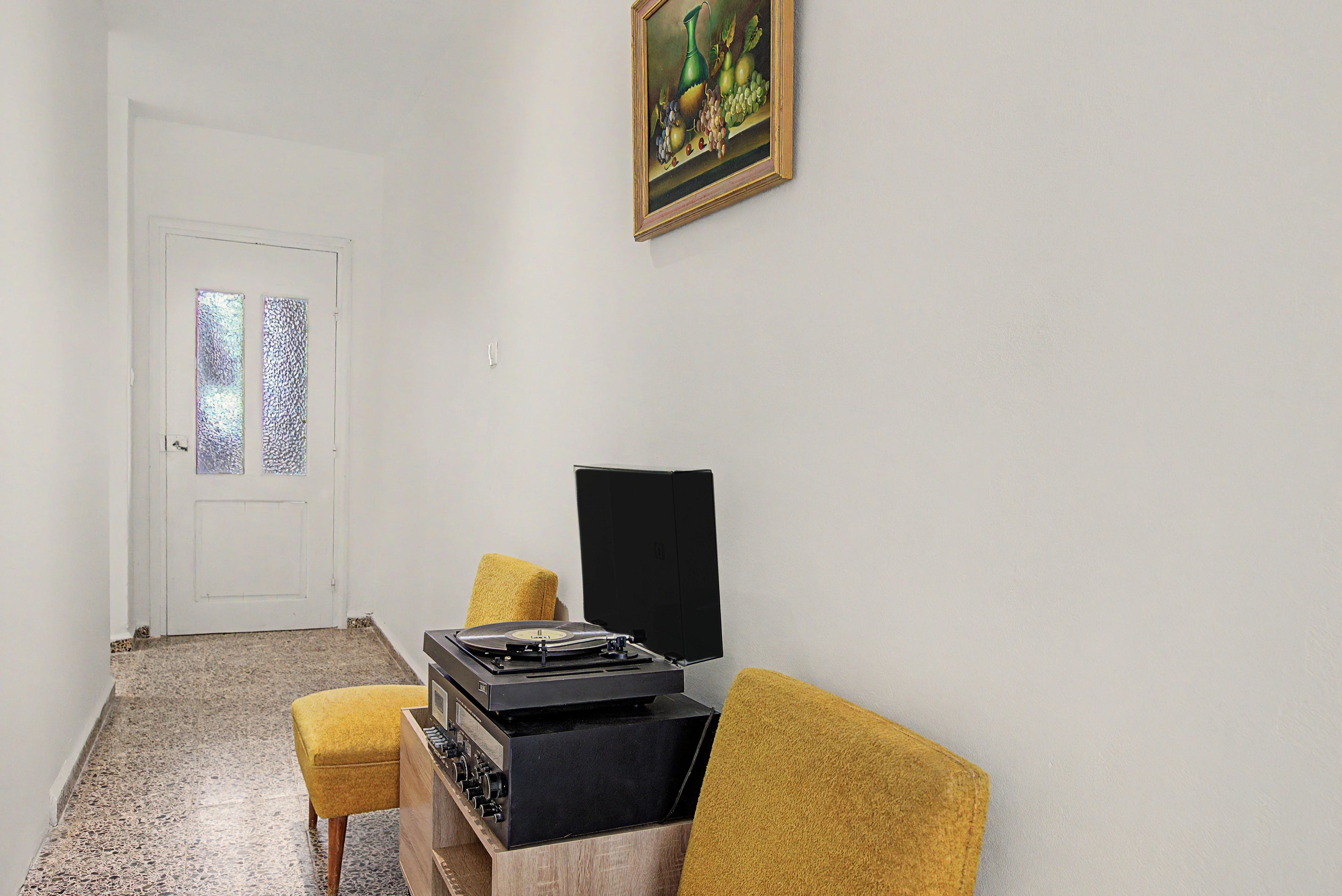 A room with a wooden cabinet, a yellow armchair, a black television, and a door with frosted glass panels.