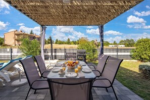An outdoor patio with a table set for breakfast, surrounded by chairs, and a pergola overhead. - Villa Blue Lagoon, Labin, Croatia (Labin)