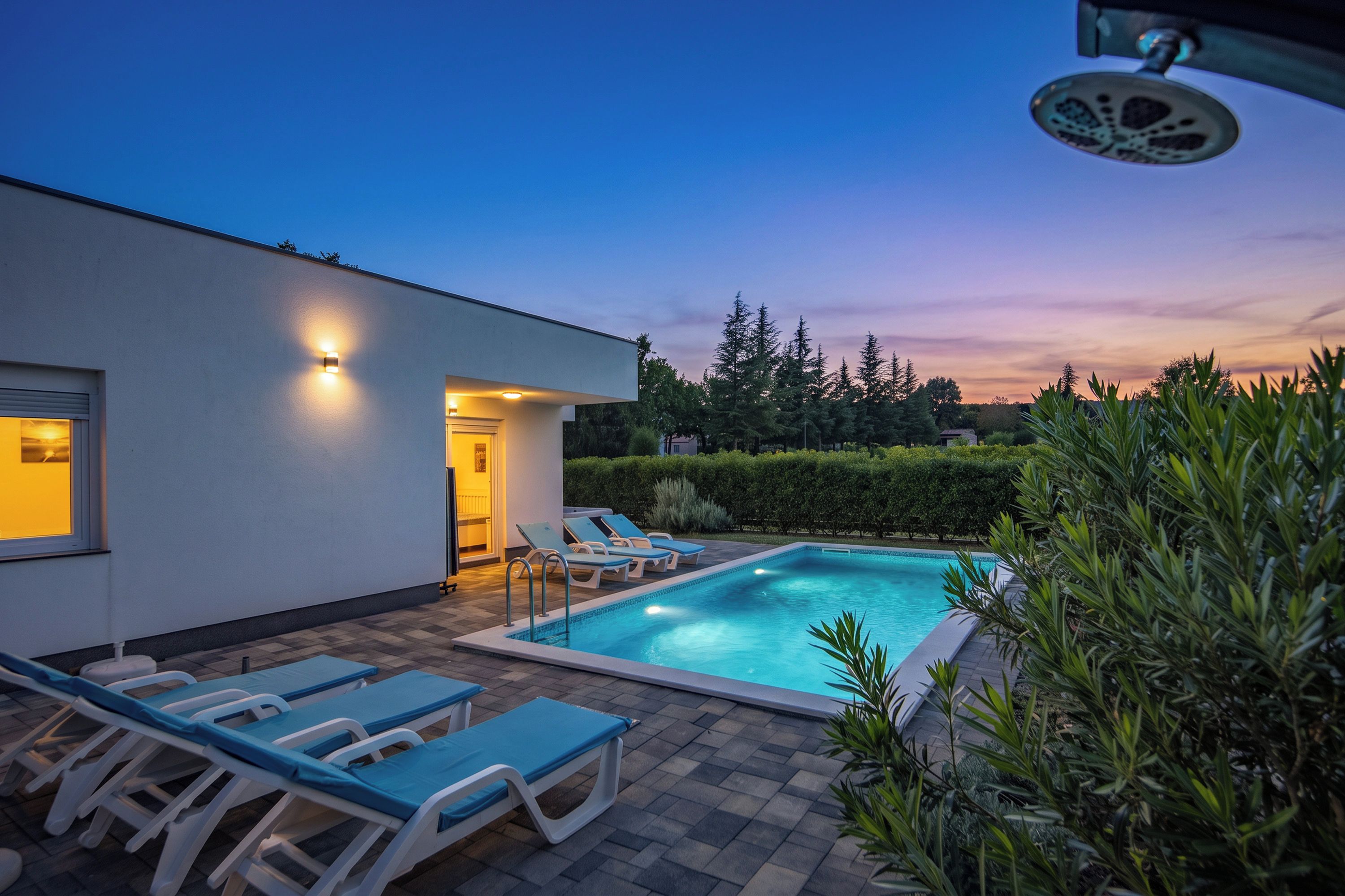Uma área de piscina moderna ao ar livre, com espreguiçadeiras e entrada bem iluminada.