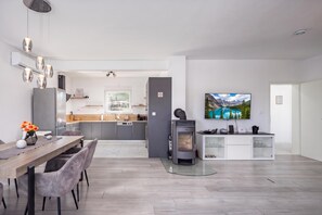A modern kitchen with grey cabinets, a dining area with a wooden table and chairs, and a large flat-screen TV mounted on the wall. - Villa Blue Lagoon, Labin, Croatia (Labin)