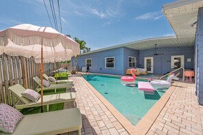 Ein Garten mit Swimmingpool, Liegestühlen und einer überdachten Terrasse.