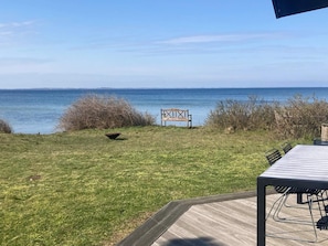 A deck with a view of the sea, a wooden bench, and a table with chairs. - 4 Star Holiday Home in Martofte (Martofte)