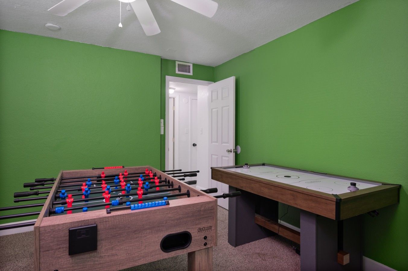 A room with a foosball table and a pool table.