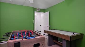 A room with a foosball table and a pool table.