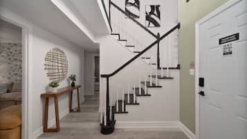 A staircase with a black handrail and white steps, leading to a door with a 'Please Keep Door Closed Quiet Hours' sign.