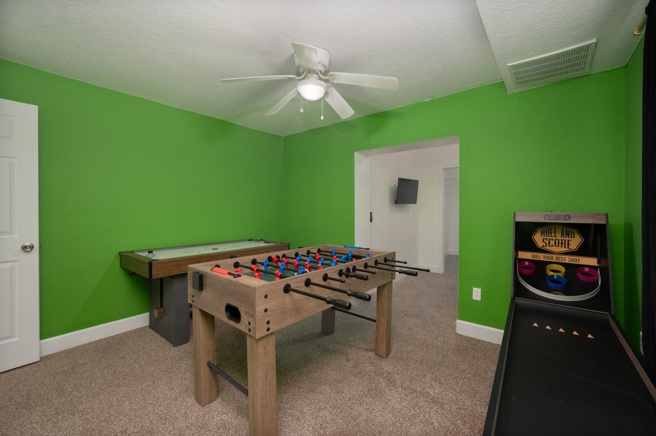 Una habitación con mesa de fútbol de mesa, mesa de billar y juego de disparos de fútbol de mesa.