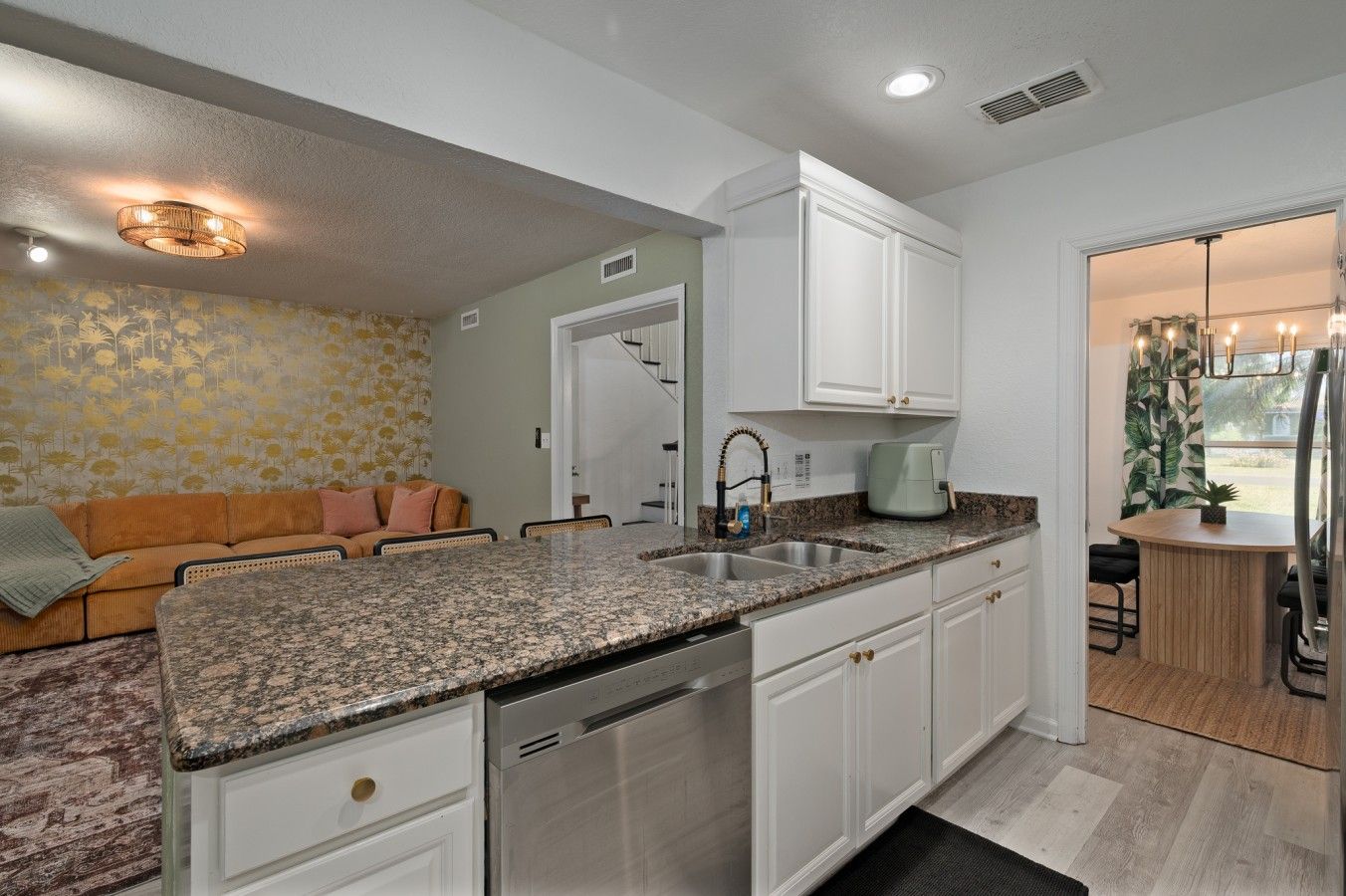 A modern kitchen with granite countertops, stainless steel appliances, and white cabinetry.