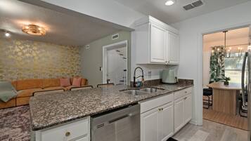 A modern kitchen with granite countertops, stainless steel appliances, and white cabinetry.