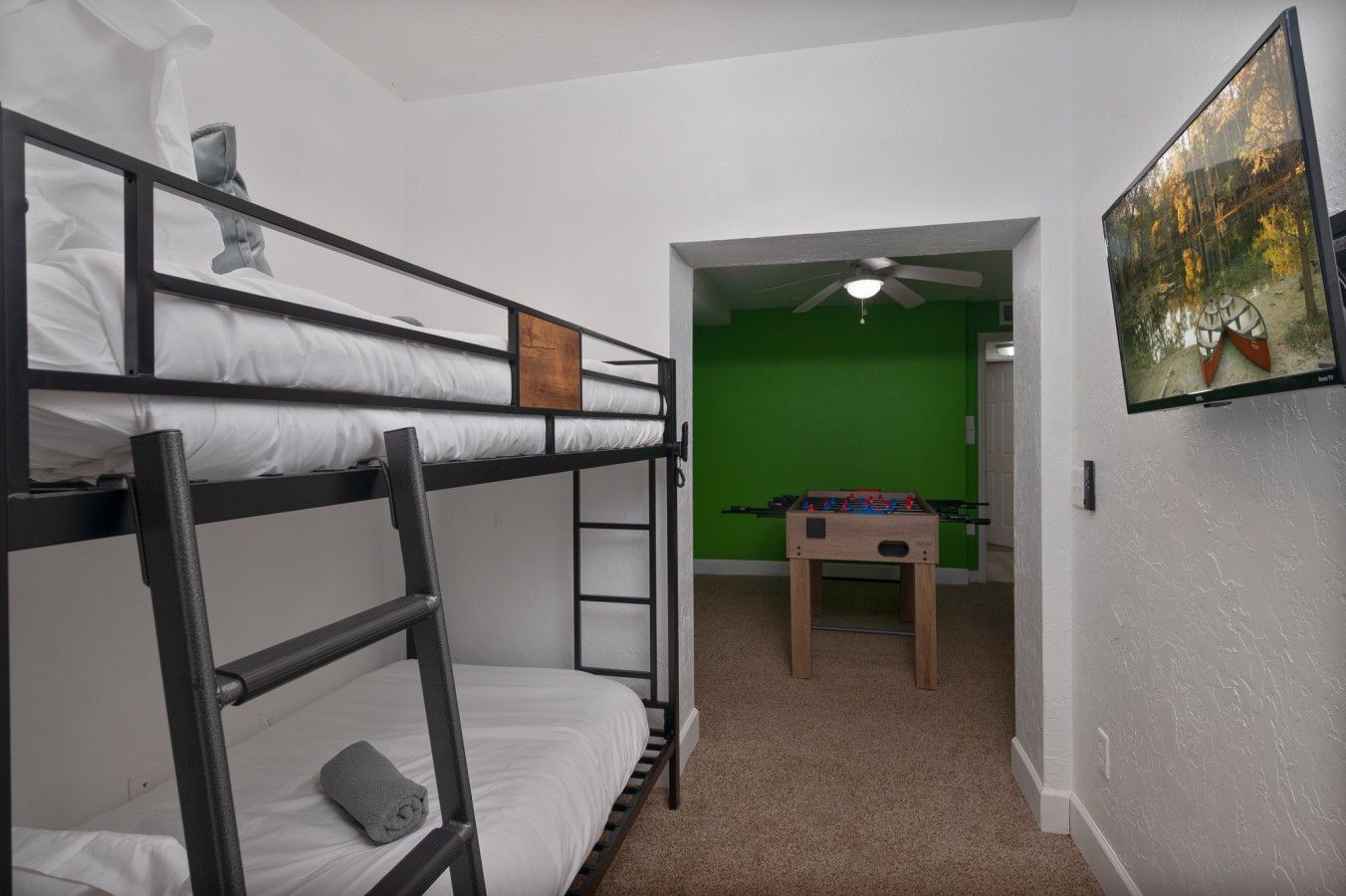 A bunk bed room with a foosball table and a green screen wall.