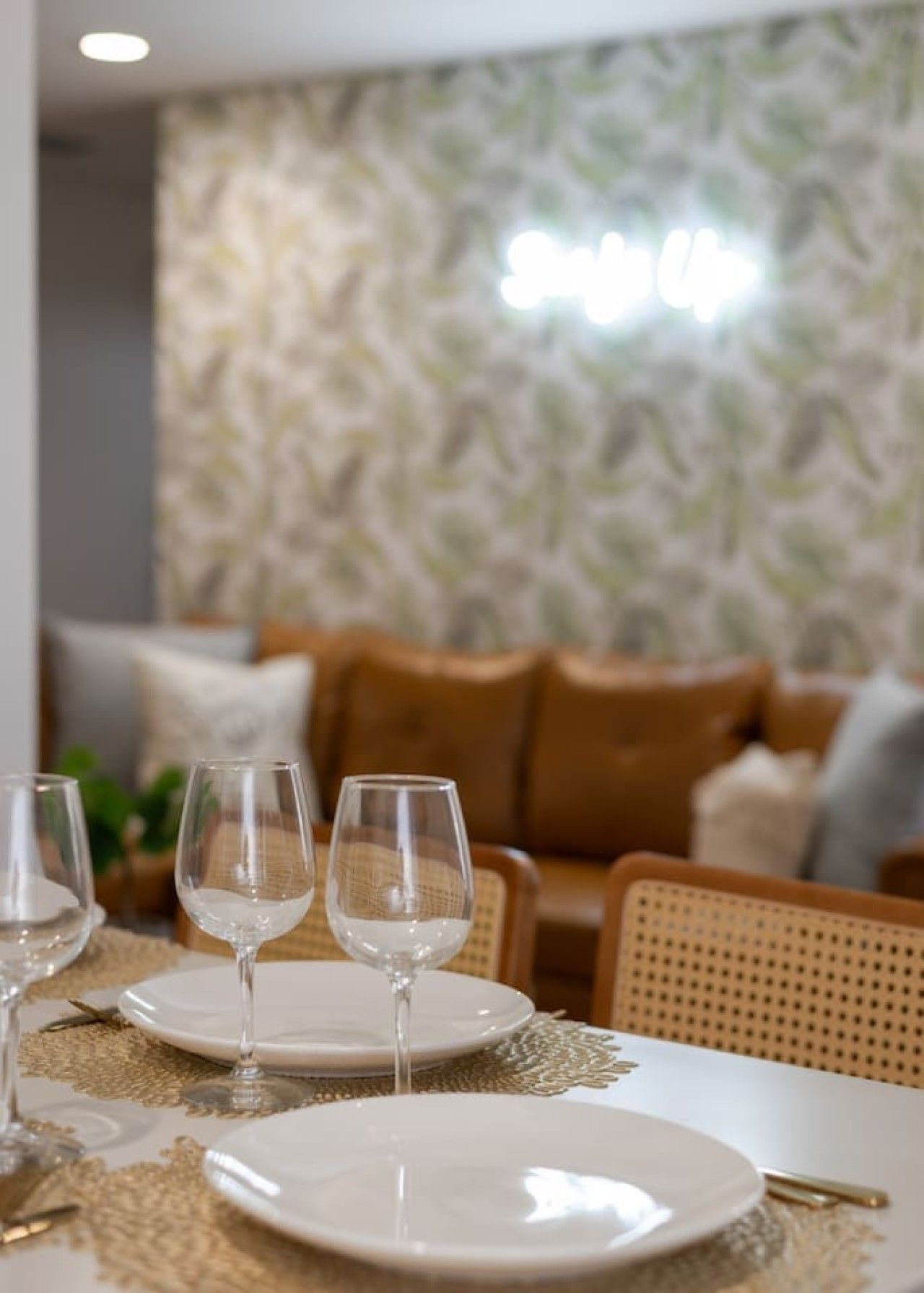 A dining area with a table set for two, two wine glasses, and a plate.