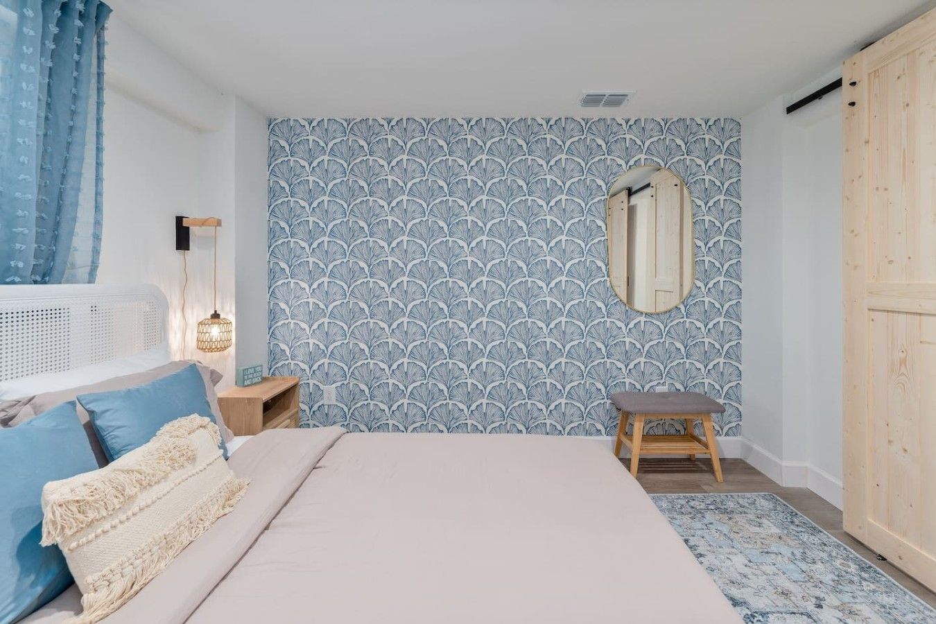 Une chambre à coucher avec un lit, une table de chevet, une lampe et un miroir au mur.