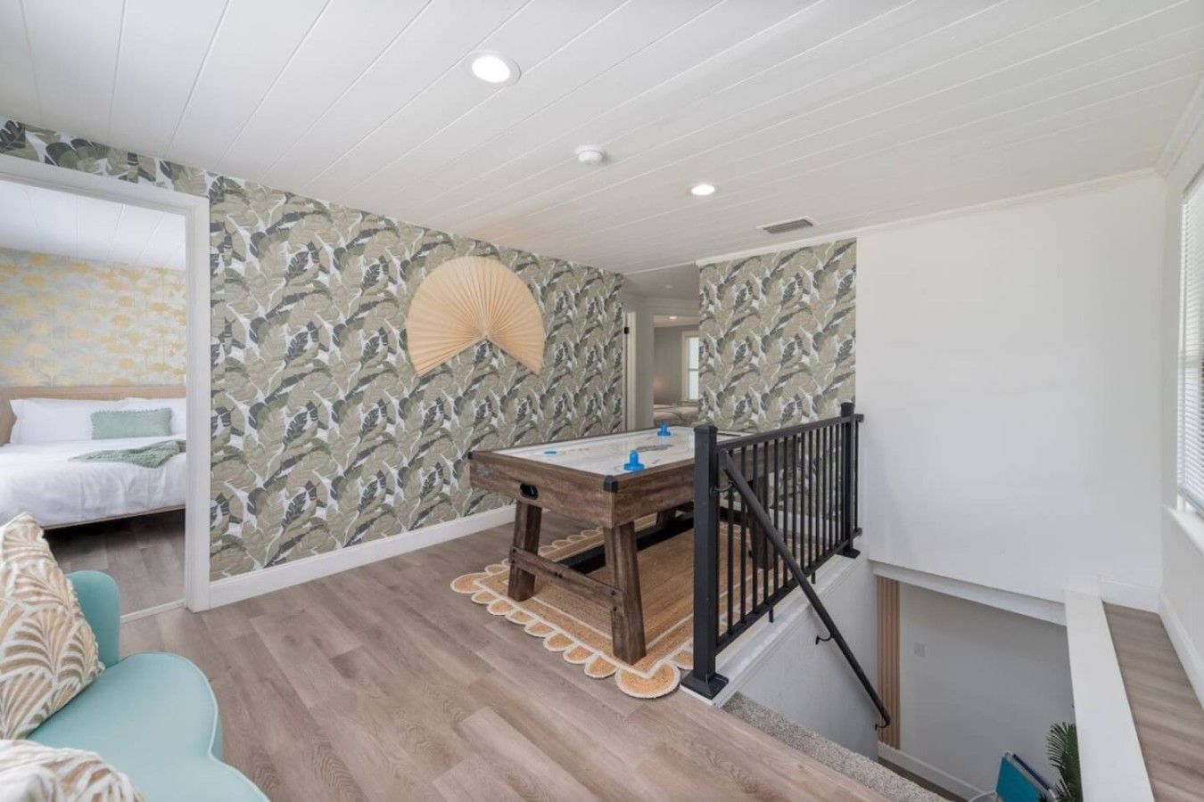 Ein Zimmer mit einem Bett, einem Holztisch mit Spüle, einer Wand mit Muster und einer Treppe mit Geländer.
