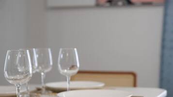 A dining table with plates and wine glasses, a woven placemat, and a painting of a pink car on the wall.