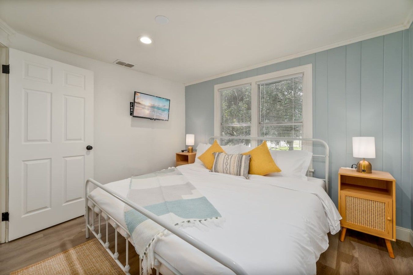 A bedroom with a bed, bedside tables, a window, and a door.