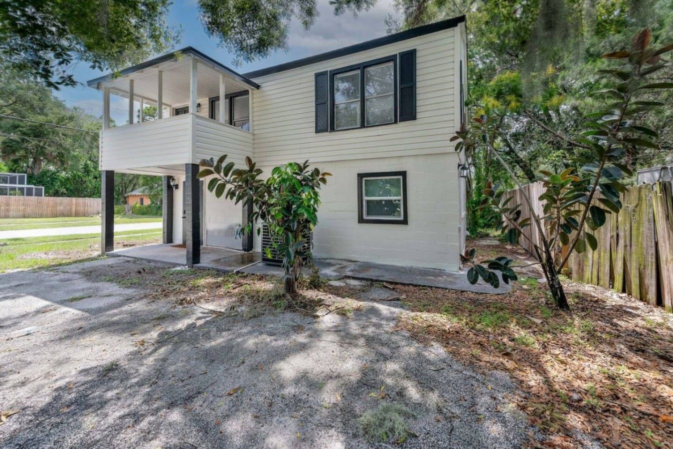 A two-story house with a covered porch and a small garden.