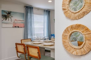 Una zona de menjador amb una taula preparada per a quatre, dues cadires i una finestra amb cortines blaves.