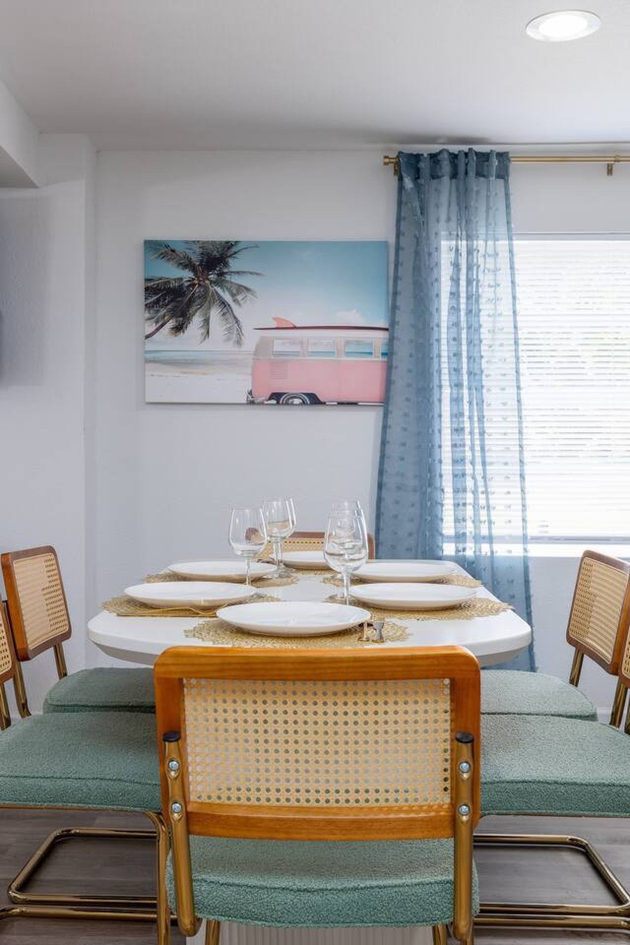 Un coin repas avec une table ronde dressée pour quatre personnes, agrémentée d’assiettes blanches et de touches dorées.