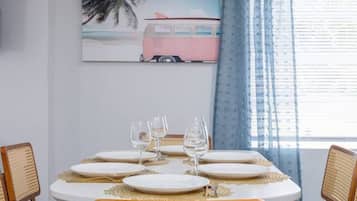 Een eetgedeelte met een ronde tafel voor vier personen, met witte borden en gouden details.