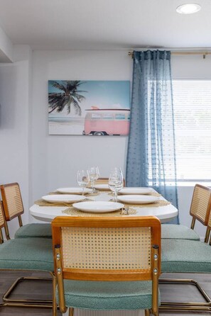 Un coin repas avec une table ronde dressée pour quatre personnes, agrémentée d’assiettes blanches et de touches dorées.
