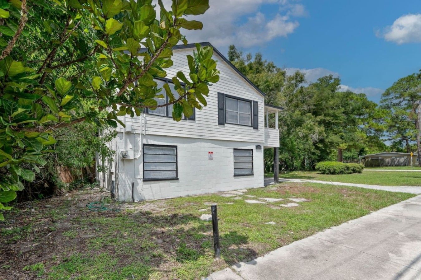 A single-story house with a garage, surrounded by greenery and a clear sky.