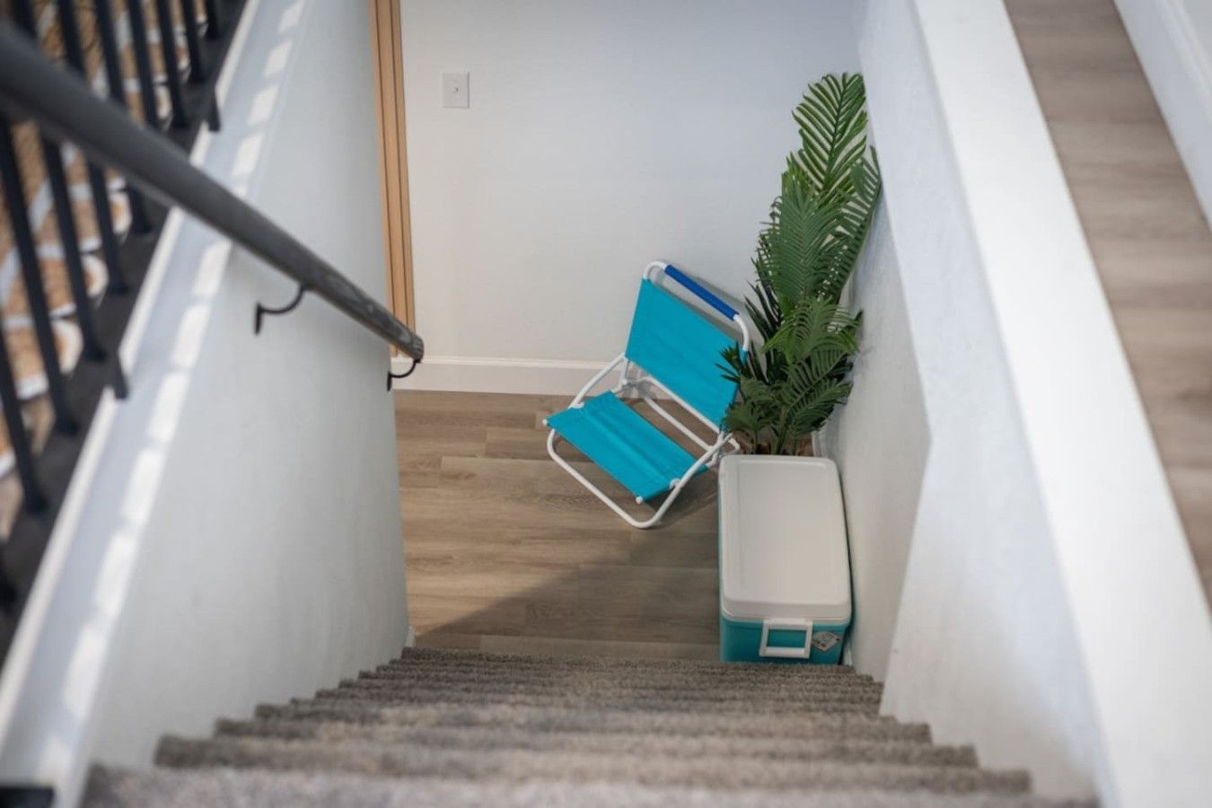 A staircase with a blue chair and a white planter.