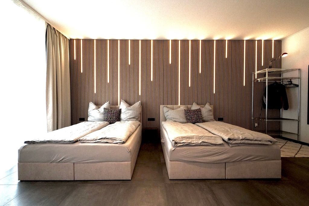 Ein modernes Hotelzimmer mit zwei Betten, einem Kleiderschrank und einem Spiegel.