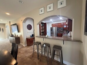 A modern kitchen with stainless steel appliances, a marble countertop, and a dining area with a dark wooden table. - 4 bedroom house with pool and boat parking, minutes from the Colorado River. (Fort Mohave)