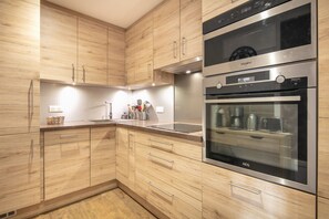 Eine moderne Küche mit Holzschränken, Edelstahlgeräten und einem eingebauten Backofen.