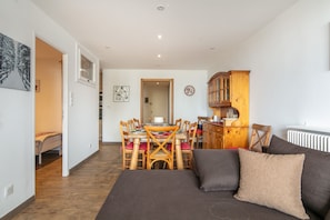 Un salon moderne comprenant un canapé, une table à manger avec des chaises, un meuble en bois et un radiateur.