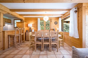 Un interior de madera con comedor, cocina y grandes ventanales.