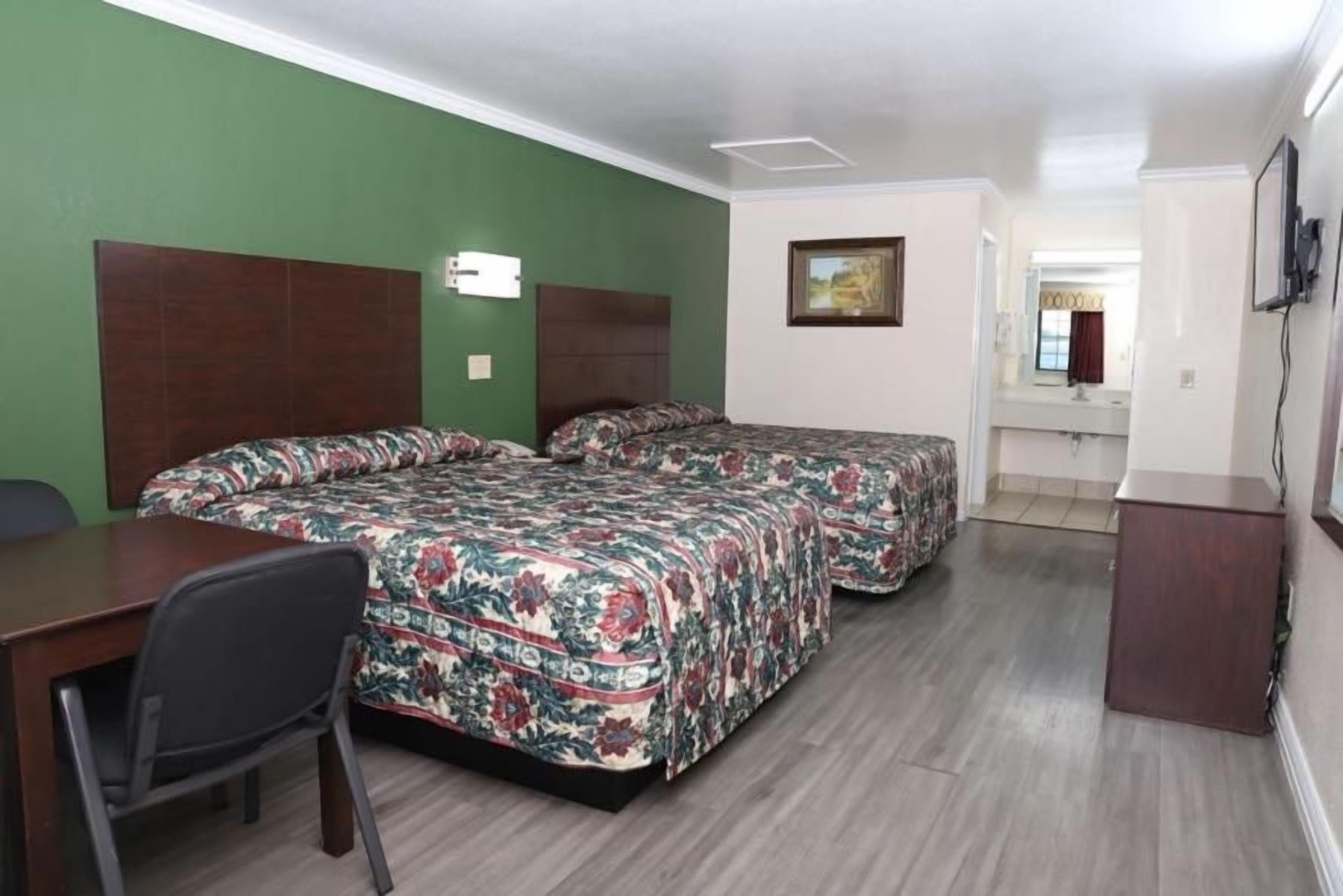 A hotel room with two beds, a desk, and a chair.