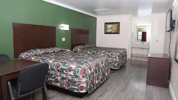 A hotel room with two beds, a desk, and a chair.