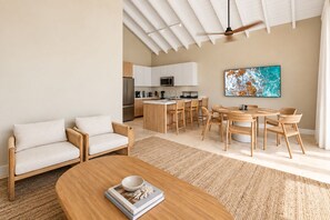 A modern living room with a sofa, coffee table, and dining area with chairs. - Bungalow with pool in georgetown, sleeps 6 people! (Exuma)