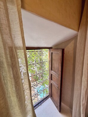 A narrow corridor with a wooden door and a metal gate leading to an outdoor area. - Exceptional private riad with a pool in Mouassine, in the heart of the Medina (Marrakech)