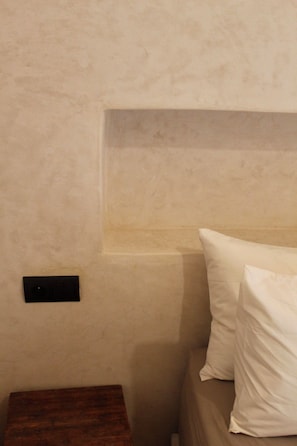 Una habitación con una cama, una mesita de noche y una estantería en la pared.