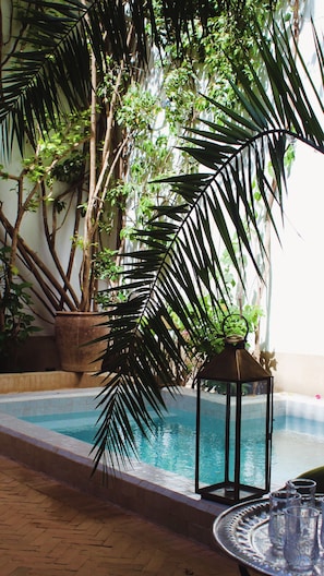 An indoor pool area with a tiled floor, a lantern, and potted plants. - Exceptional private riad with a pool in Mouassine, in the heart of the Medina (Marrakech)