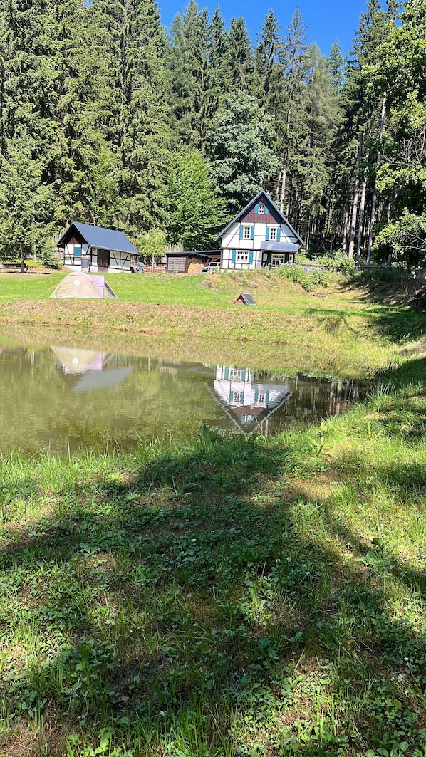 Una propietat a la vora d'un llac, amb una casa, un edifici petit i una tenda.