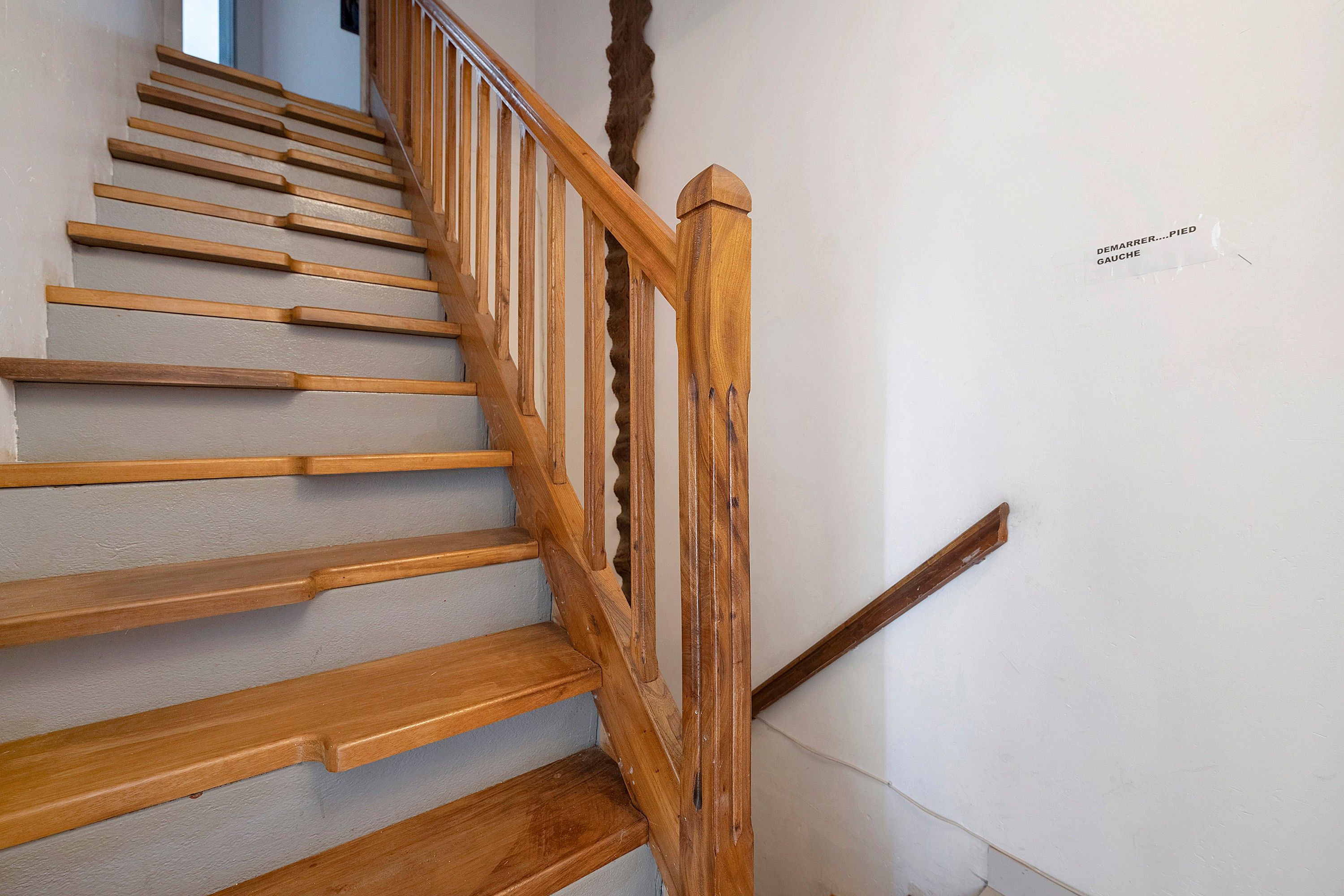 Eine Holztreppe mit Handlauf und einem Schild an der Wand.