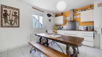 Een keuken met een houten tafel, een bankje, witte kastjes en een hanglamp.