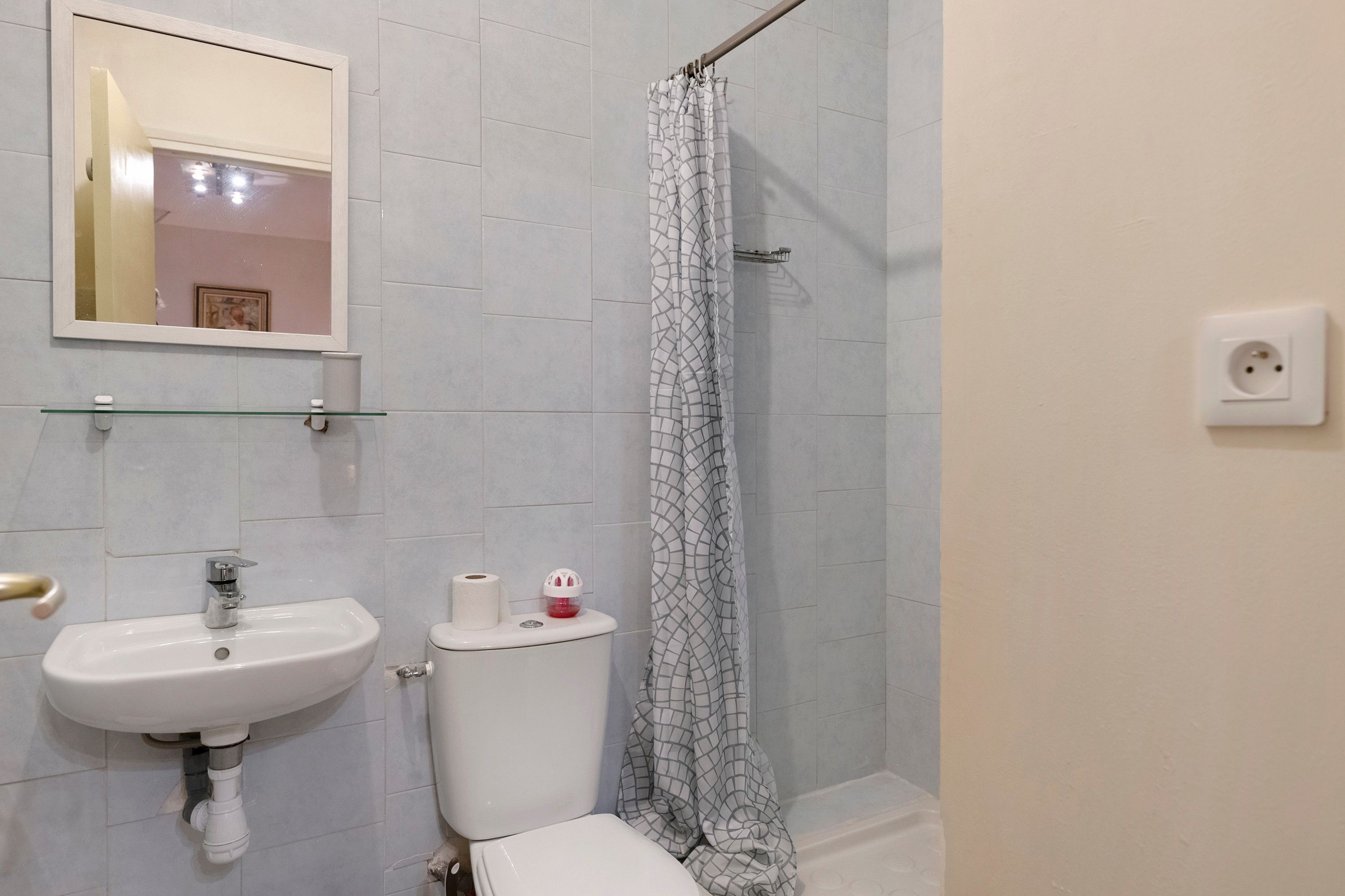 A bathroom with a white sink, a toilet, and a shower curtain.