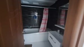 A bathroom with a bathtub, a white sink, and a mirror. - Fully Furnished 1-bedroom Apartment in Khezama Prime Location (Sousse)
