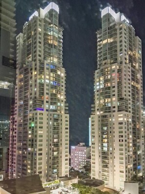 Deux immeubles de grande hauteur, dotés de nombreux étages et de balcons, éclairés par un système d’éclairage artificiel.
