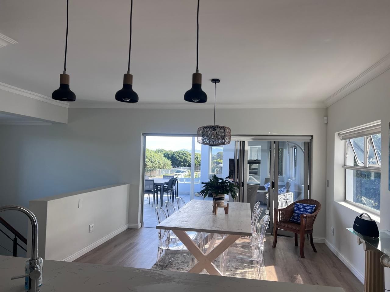 A modern kitchen with a dining area, a sliding glass door leading to a patio, and pendant lighting.