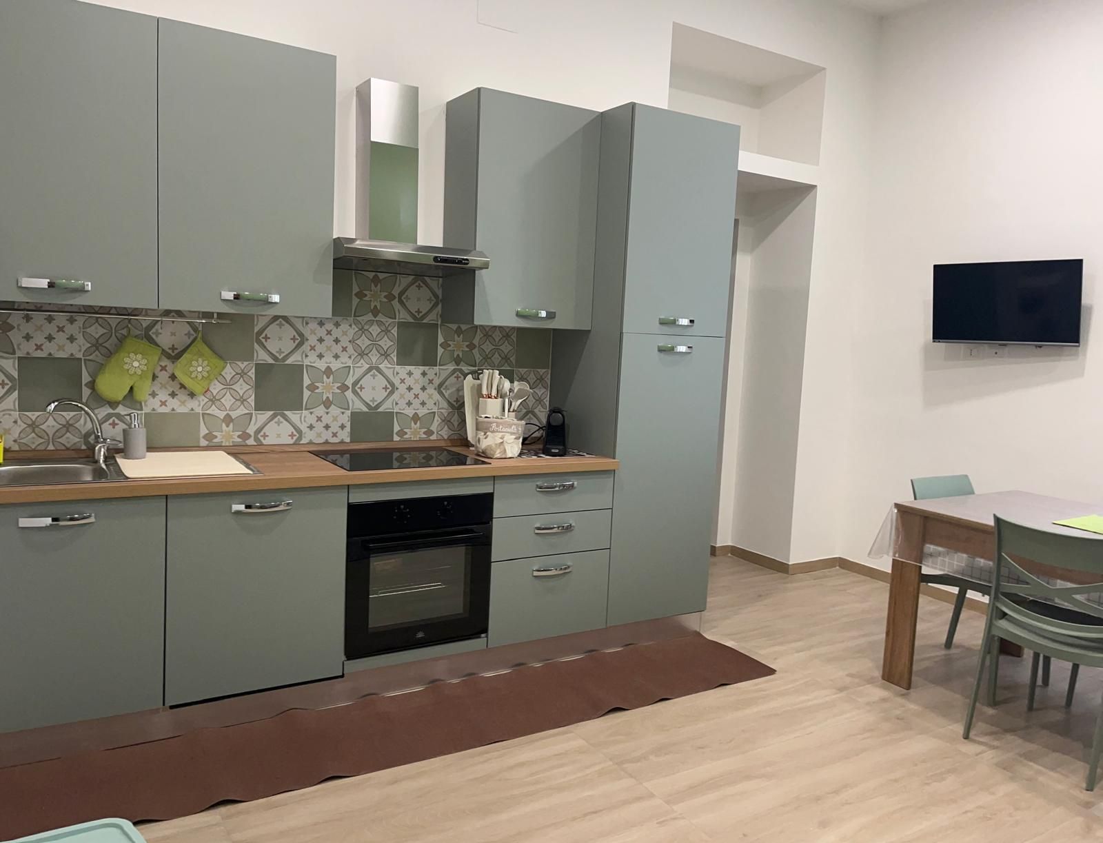 A modern kitchen with grey cabinets, a wooden countertop, and a built-in oven.