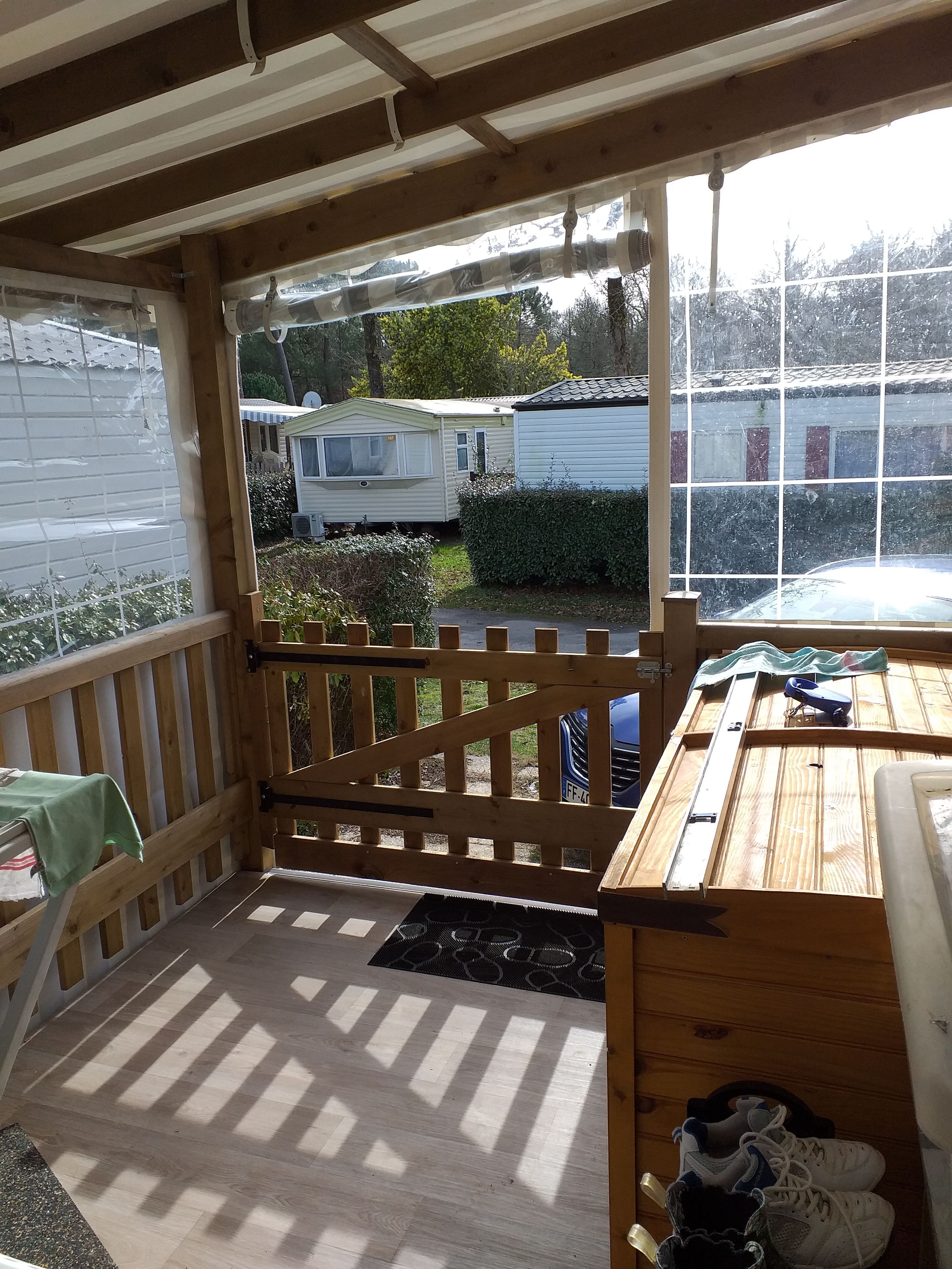 A wooden deck with a view of a mobile home and a house.